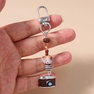 Macro detail of a miniature camera pendant with mixed decorative beads on a lanyard