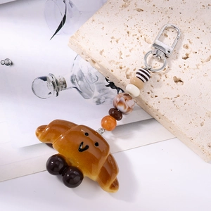 Detailed view of croissant keychain with decorative beads and silver metal ring