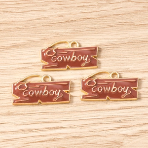 Close-up of brown enamel cowboy pendants with gold lettering for DIY jewelry making