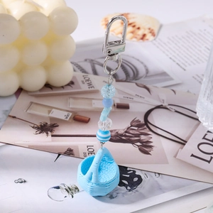 Close-up of blue beaded keychain with woven basket charm on magazine background