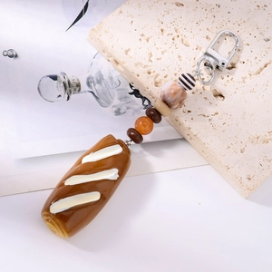 Macro detail of artificial bread keychain with colorful beads and silver lobster clasp