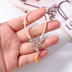 Detailed view of handmade woven phone strap with realistic croissant pendant and metal clasp