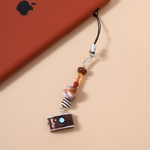 Close-up of vintage camera pendant and colorful beads on a phone strap attachment