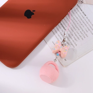 Détail d'un bijou de téléphone rose avec nœud et panier tressé à pois et crochet