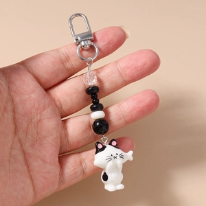 Detail of cute cat keychain with striped beads, plush ball, and silver metal clasp
