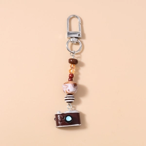 Close-up of vintage camera keychain with turquoise beads and marble texture charms