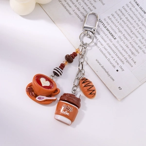 Detailed close-up of coffee cup, croissant charm, and heart latte art on a silver keychain