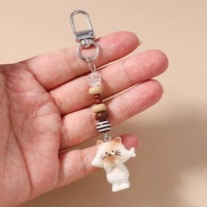 Detail of cute cat resin charm and striped beads on a silver metal lobster keychain