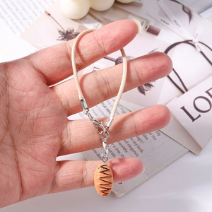 Close-up of a creative miniature bread pendant on a cream braided phone strap with metal clasp