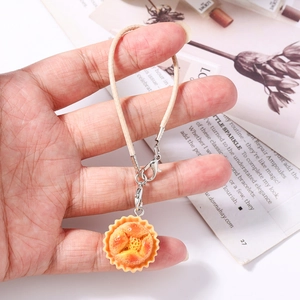 Detailed view of realistic egg tart food charm with premium woven strap and lobster clasp