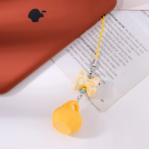 Vue détaillée d'un pendentif jaune avec nœud et panier attaché à un smartphone orange