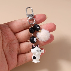 Detailed view of striped bead keychain with cute cat charm and soft pink faux fur pompom
