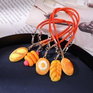 Macro detail of five realistic artificial bread charms with orange lanyards on a blue tray
