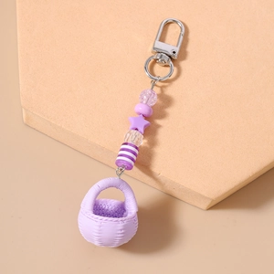 Macro detail of purple star beads and woven basket pendant on a metallic keychain