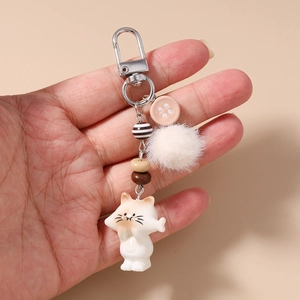 Close-up of cute cat keychain with striped beads and soft white faux fur pompom ball