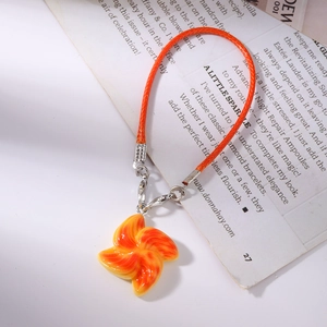 Detailed macro view of orange windmill charm with high gloss finish and woven lanyard