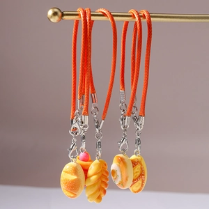 Detailed view of realistic miniature bread charms with orange lanyards hanging in a row