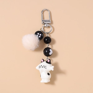 Detailed view of cat keychain with pink faux fur pompom and black striped beads