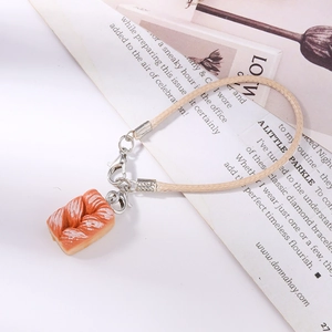 Creative twisted pastry charm with silver lobster clasp on aesthetic magazine background