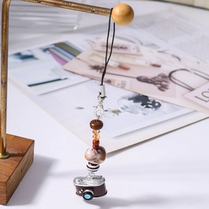 Macro detail of beaded charm with vintage camera pendant and marble texture beads