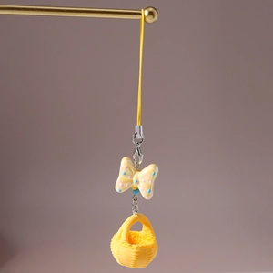 Détail d'un porte-clés nœud jaune avec un mini panier tressé et un fermoir mousqueton métal