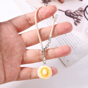Detailed view of simulated fried egg phone strap with braided lanyard held in hand