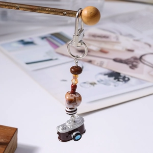 Detailed view of vintage brown camera charm with diverse decorative beads and silver lobster clasp