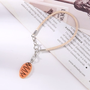 Macro detail of realistic bread charm with lobster clasp on beige braided strap