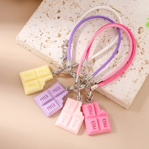 Bijoux de téléphone en forme de chocolat aux tons pastel sur un plateau décoratif en pierre