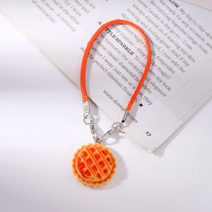 Macro detail of realistic orange lattice pie pendant with silver clip and orange woven strap