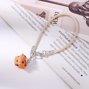 Detail of creative resin cupcake pendant with orange cream design on woven phone strap
