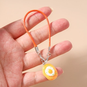 Detailed close-up of a braided orange mobile phone strap with a fried egg resin charm