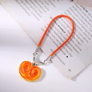 Macro shot of a realistic orange pastry keychain with woven strap on a magazine background