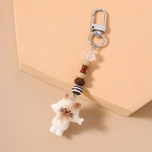 Detail of cute white cartoon cat keychain with striped beads and silver lobster clasp