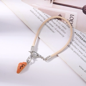 Close-up of realistic croissant charm on a beige braided mobile phone strap cord