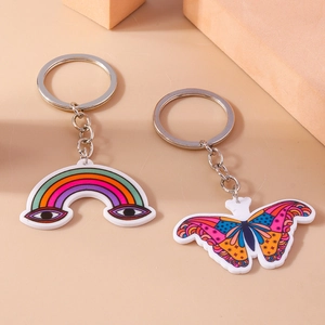 Portachiavi in acrilico arcobaleno e farfalla con anello in metallo su sfondo beige caldo