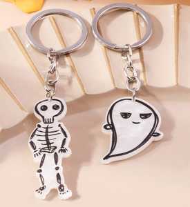 Macro view of Halloween skeleton and ghost keychains on a textured ceramic tray