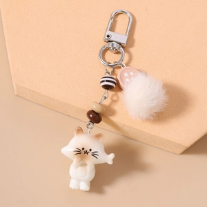 Detail of cute cat keychain featuring plush pompom, striped beads and silver clasp