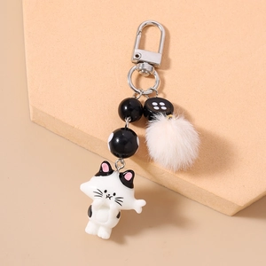 Detail of cute cat keychain with white pom-pom, black striped beads and silver metal clasp