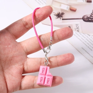Détail d'un pendentif chocolat en résine rose avec texte milk et cordon tressé