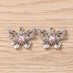 Detailansicht silberner Schmetterlingsanhänger mit rosa Herzkristallen auf Holzhintergrund