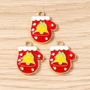 Three red enamel Christmas glove charms with golden edges and bells on wood background