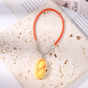 Close-up of realistic hot dog bread pendant with orange braided cord and silver lobster clasp