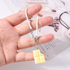 Détail d'un pendentif en forme de chocolat au lait avec cordon tressé blanc et fermoir