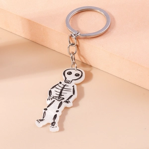 Detail of white acrylic skull keychain with silver metal ring on minimal background