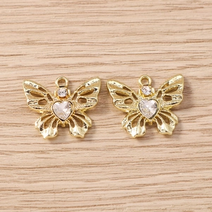 Makro-Detail goldener Schmetterlings-Schmuckanhänger mit herzförmigem Kristall auf Holz