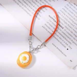 Detail of food-shaped bread and fried egg charm with orange braided phone lanyard