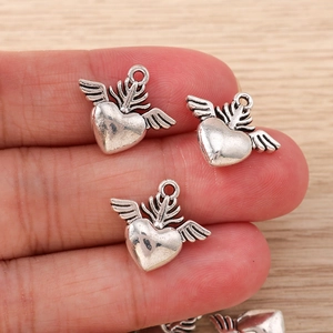 Close-up of vintage silver heart wing charms held in hand for jewelry DIY size scale