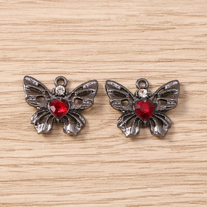 Detail von dunklen Schmetterlingsanhängern mit roten Herzsteinen und Strass für Schmuck DIY