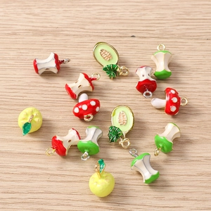 Detailansicht bunter Emaille-Anhänger mit Frucht- und Pilzmotiven auf Holzuntergrund